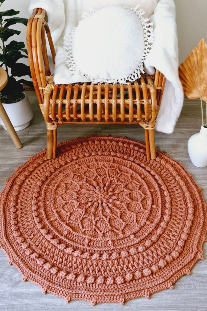 Round crochet rug in front of a cane chair.